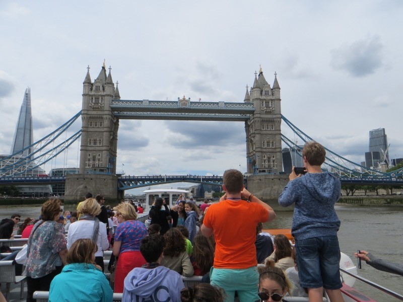 In the background is London Bridge. In the foreground we can see the backs of a group of students, all taking pictures of the famous bridge.