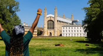 Student studying in Cambridge, celebrating in front of a Cambridge building.