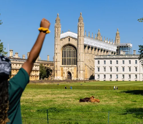Student studying in Cambridge, celebrating in front of a Cambridge building.