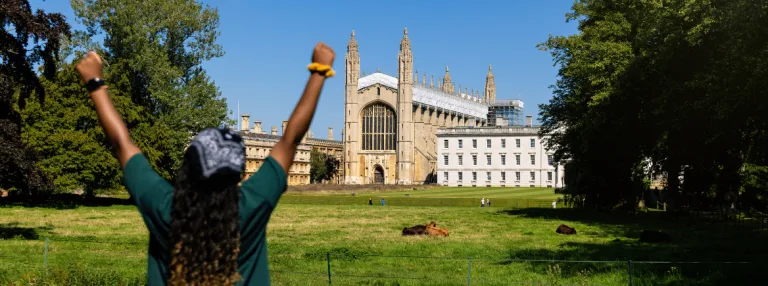 Student studying in Cambridge, celebrating in front of a Cambridge building.
